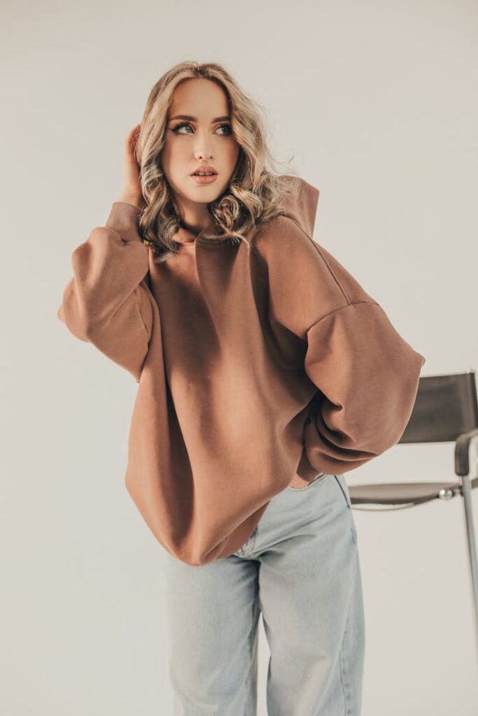Stylish woman in oversized hoodie and jeans posing elegantly indoors.